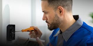 Technician installing an electronic access control system, connecting security wires and configuring access settings for restricted entry.