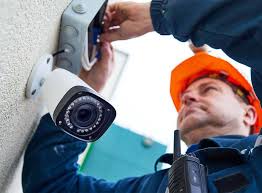 Technician mounting a high-definition security camera on a building exterior during a professional video surveillance system installation.